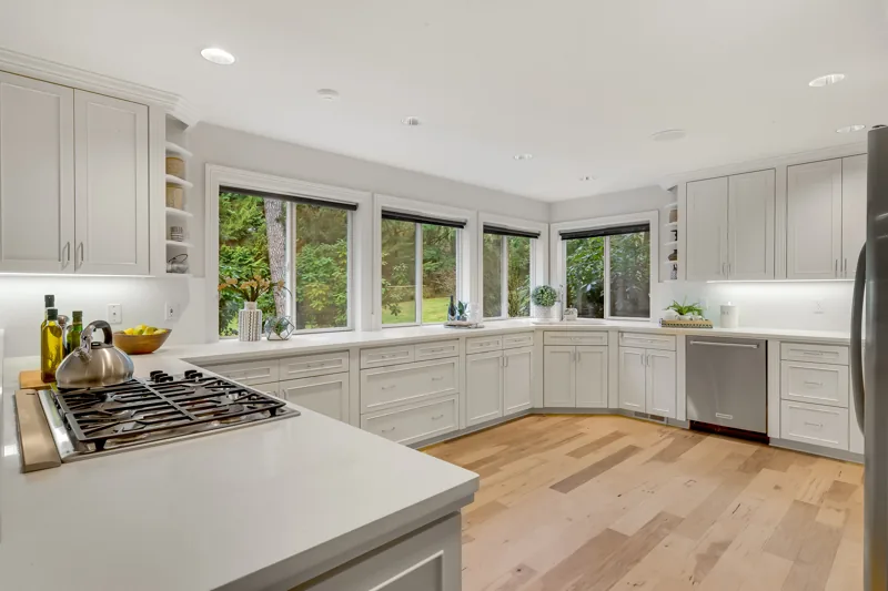 Bright kitchen with white cabinetry and broad windows