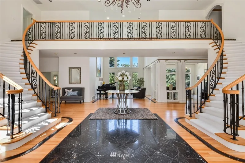 Entry hall with paired curved staircases and an upper gallery