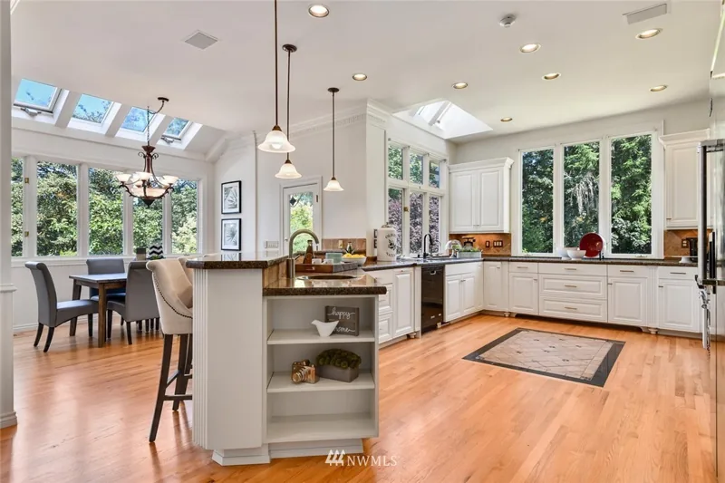 White kitchen with an island, skylights and garden-facing windows