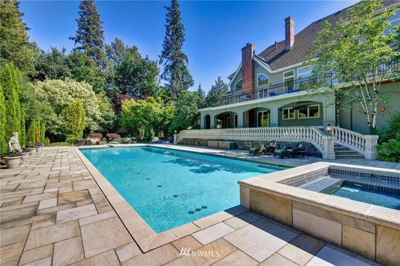 Outdoor pool and spa beside the landscaped rear of the home