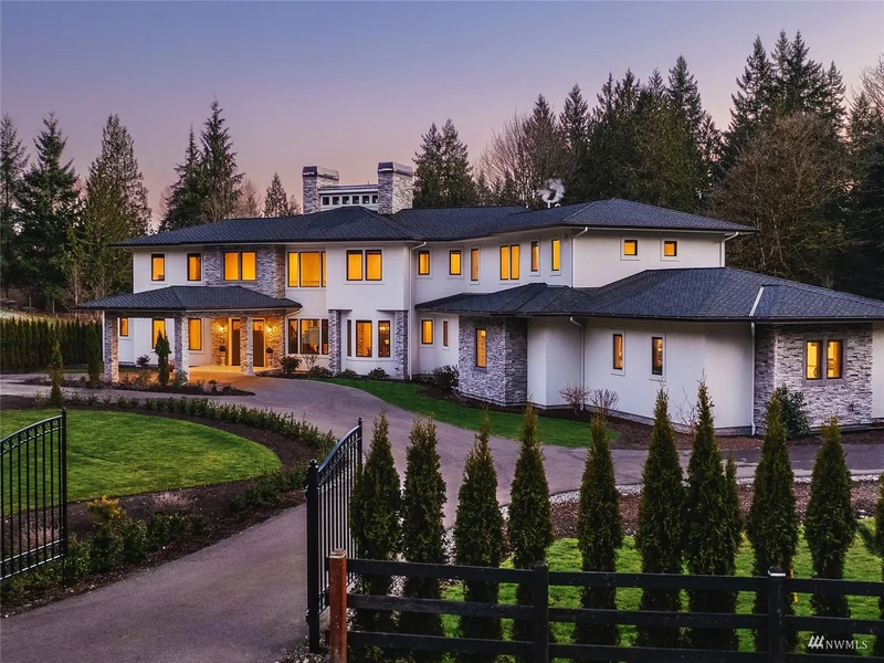 Woodinville estate exterior at dusk with a gated drive and landscaped lawn
