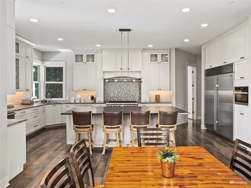 Open kitchen and dining space with white cabinetry and wood floors