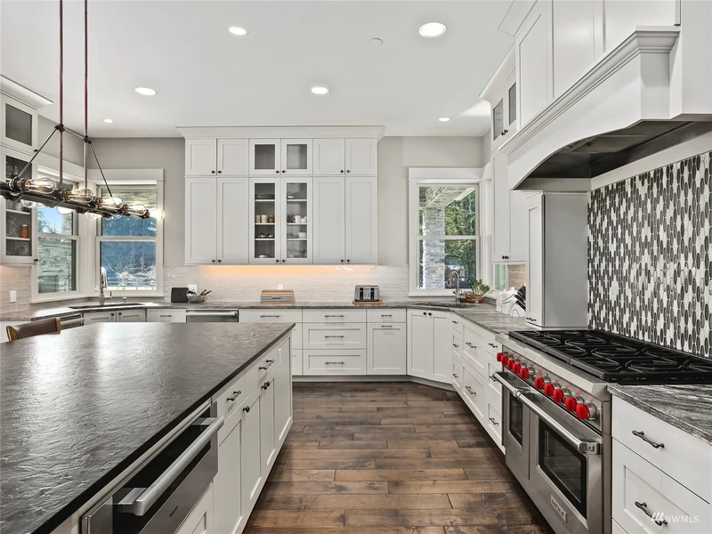 Kitchen island and cooking area with white cabinetry and a patterned backsplash