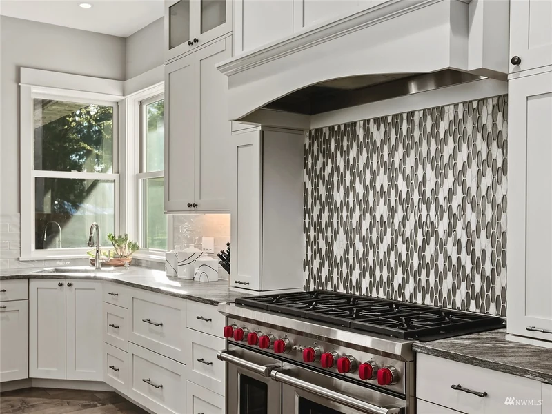 Range and decorative hood beneath a mosaic tile backsplash
