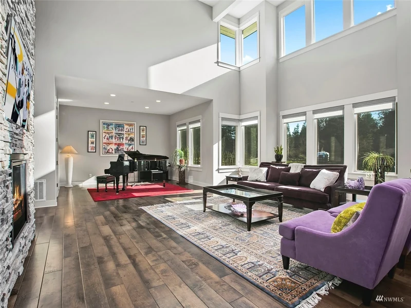 Two-story great room with tall windows and a stone fireplace