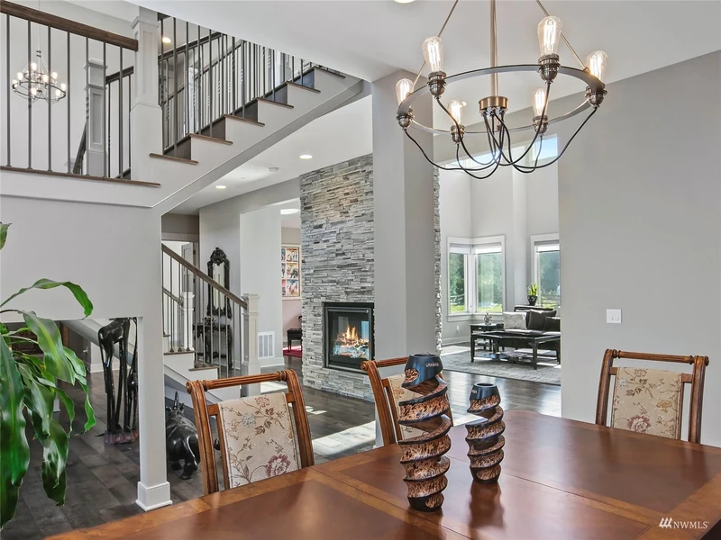 Dining space beside the open staircase and stone fireplace