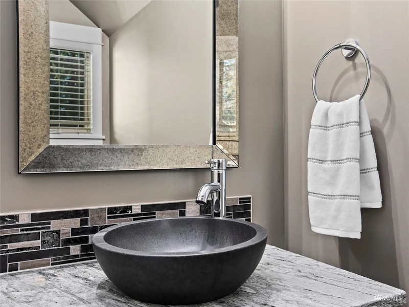 Powder room with a dark vessel sink and framed mirror