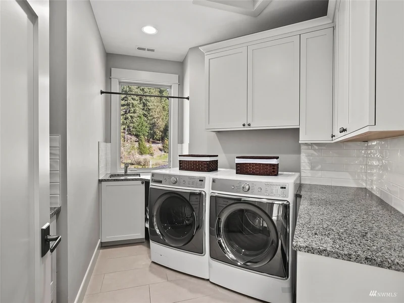 Laundry room with white cabinetry, a sink and front-loading machines