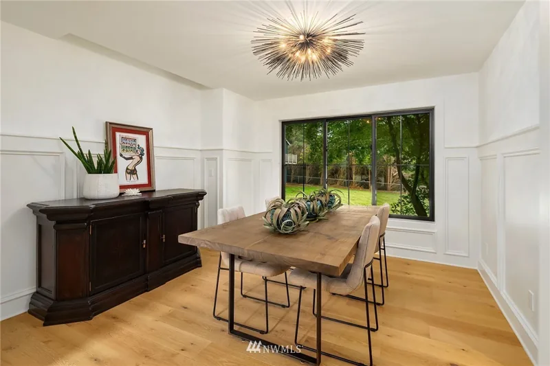 Dining room with white wall paneling and a large garden window