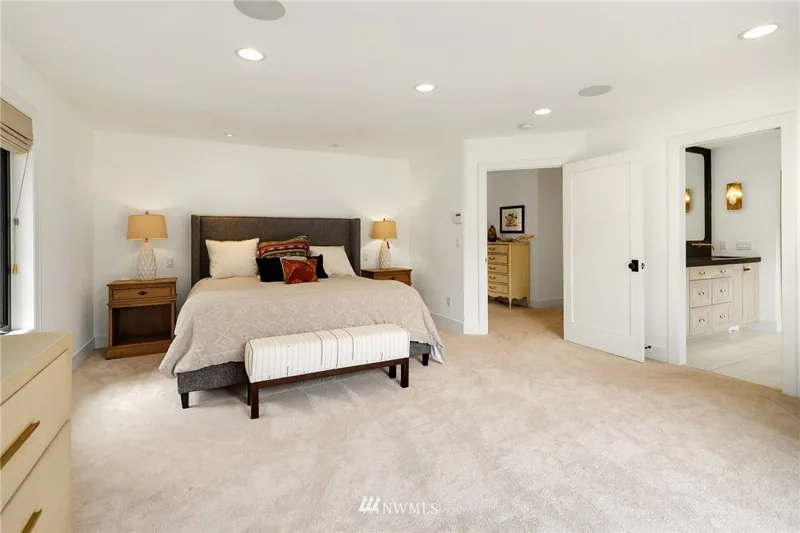 Bedroom with light carpeting and an adjoining bathroom