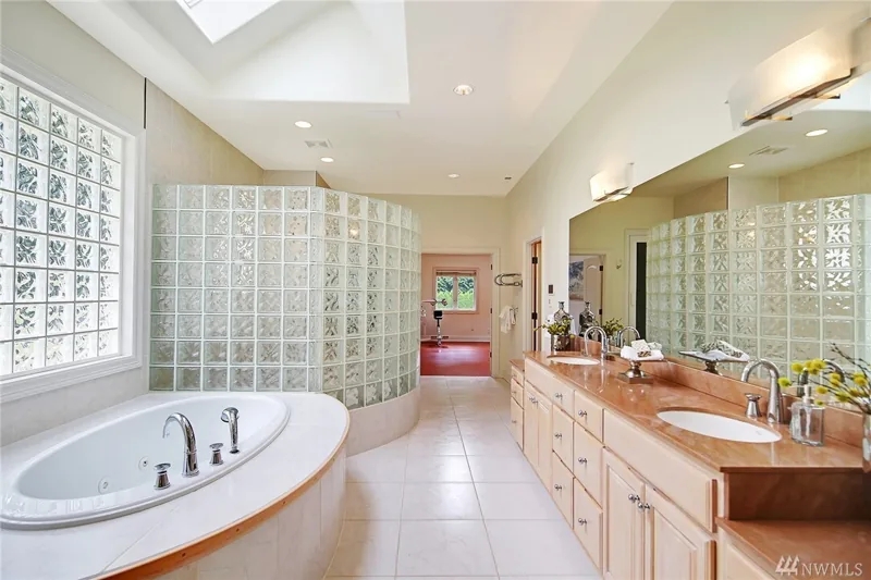 Bathroom with a curved bathtub, glass-block enclosure and long vanity
