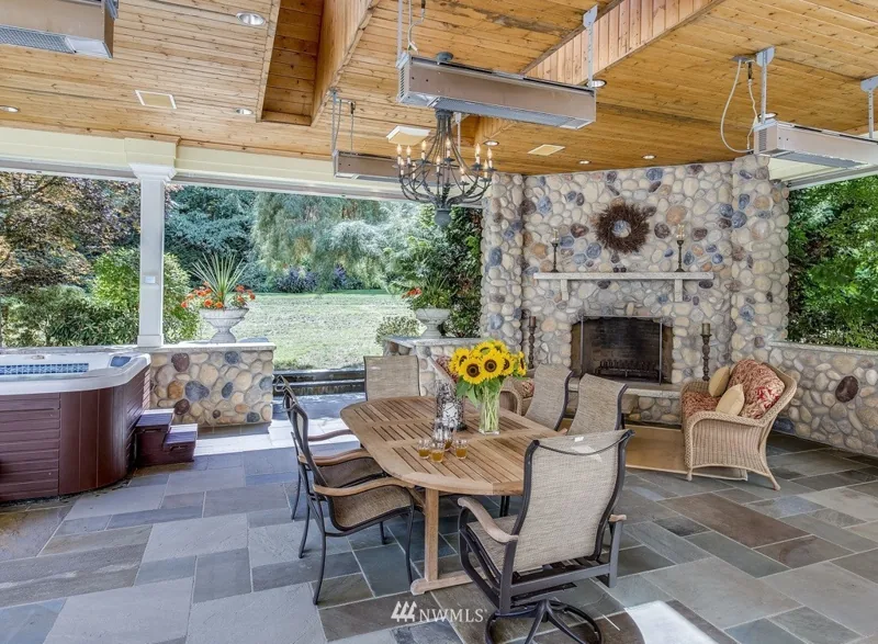 Covered outdoor seating area with a stone fireplace