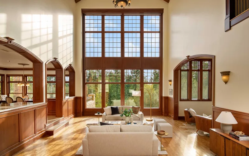 Double-height living room with tall windows and warm wood trim