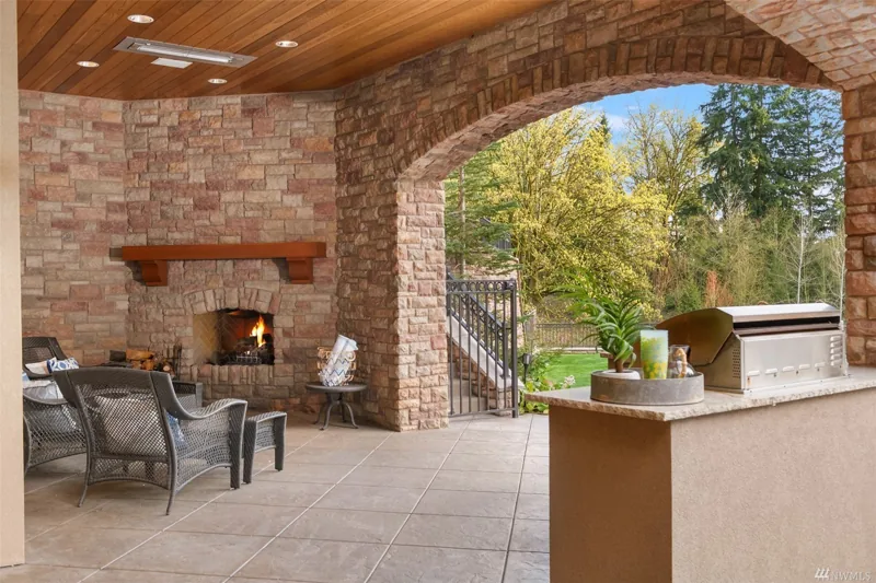 Covered stone terrace with a fireplace and outdoor kitchen