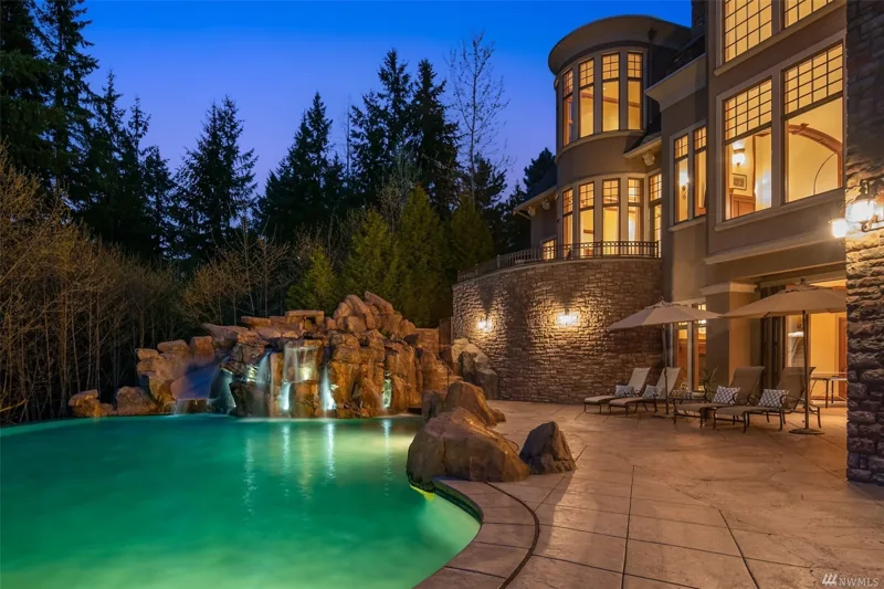 Pool and rock waterfall beside the home at dusk